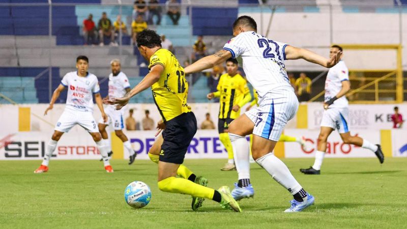 El joven delantero del Real España, Nixon Cruz, conduce el balón presionado por el defensa de Génesis Policía Nacional, Jonathan Paz.