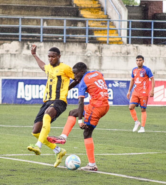 José Raúl García, de Lobos UPNFM, despeja el balón presionado por Daniel Carter Bodden del Real España.