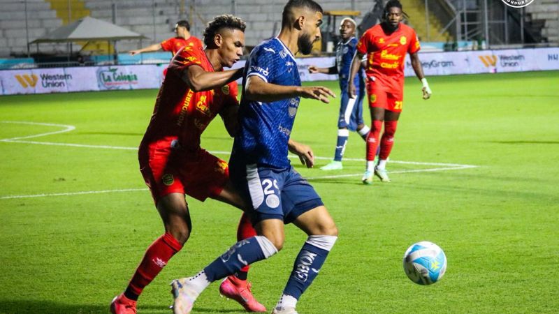 El volante de contención del Real España, Jack Baptiste, presiona al delantero brasileño de Motagua, John Kleber Oliveira.